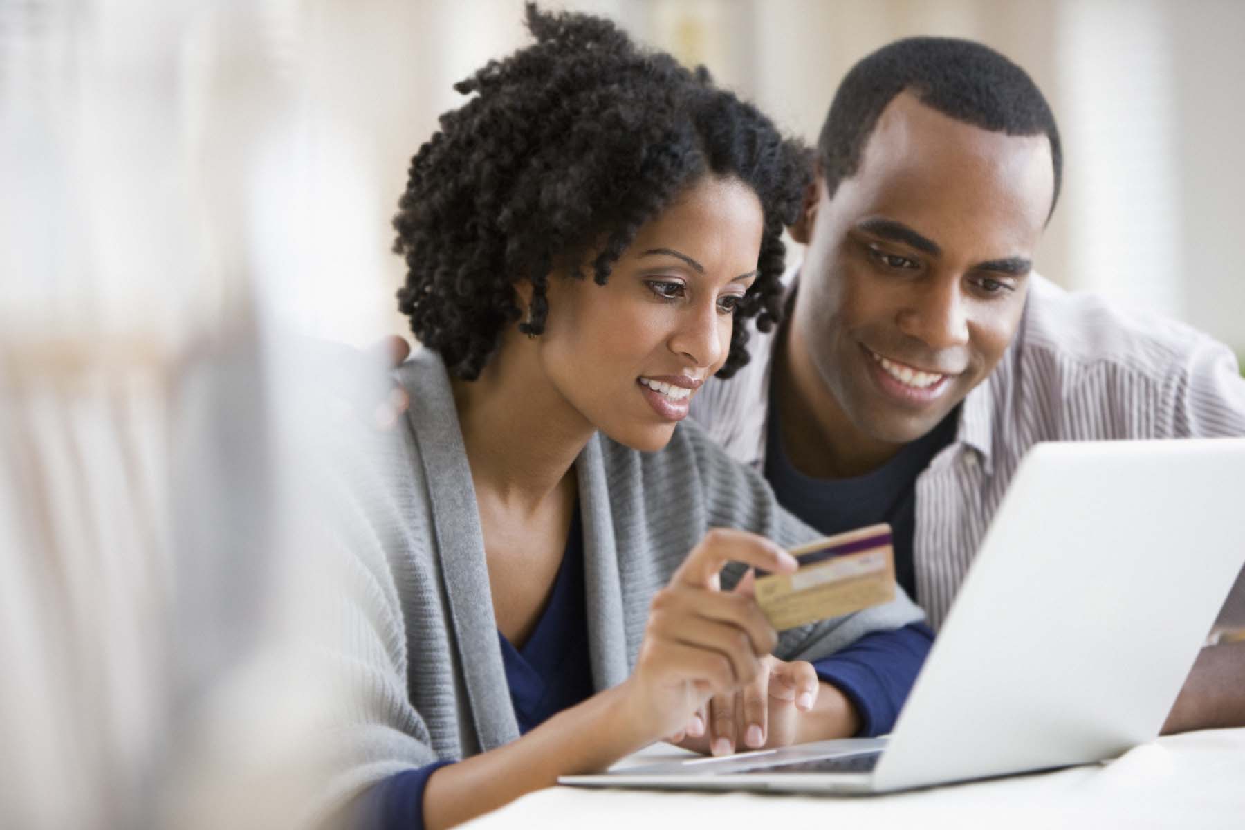 Couple using a laptop and paying with a credit card.