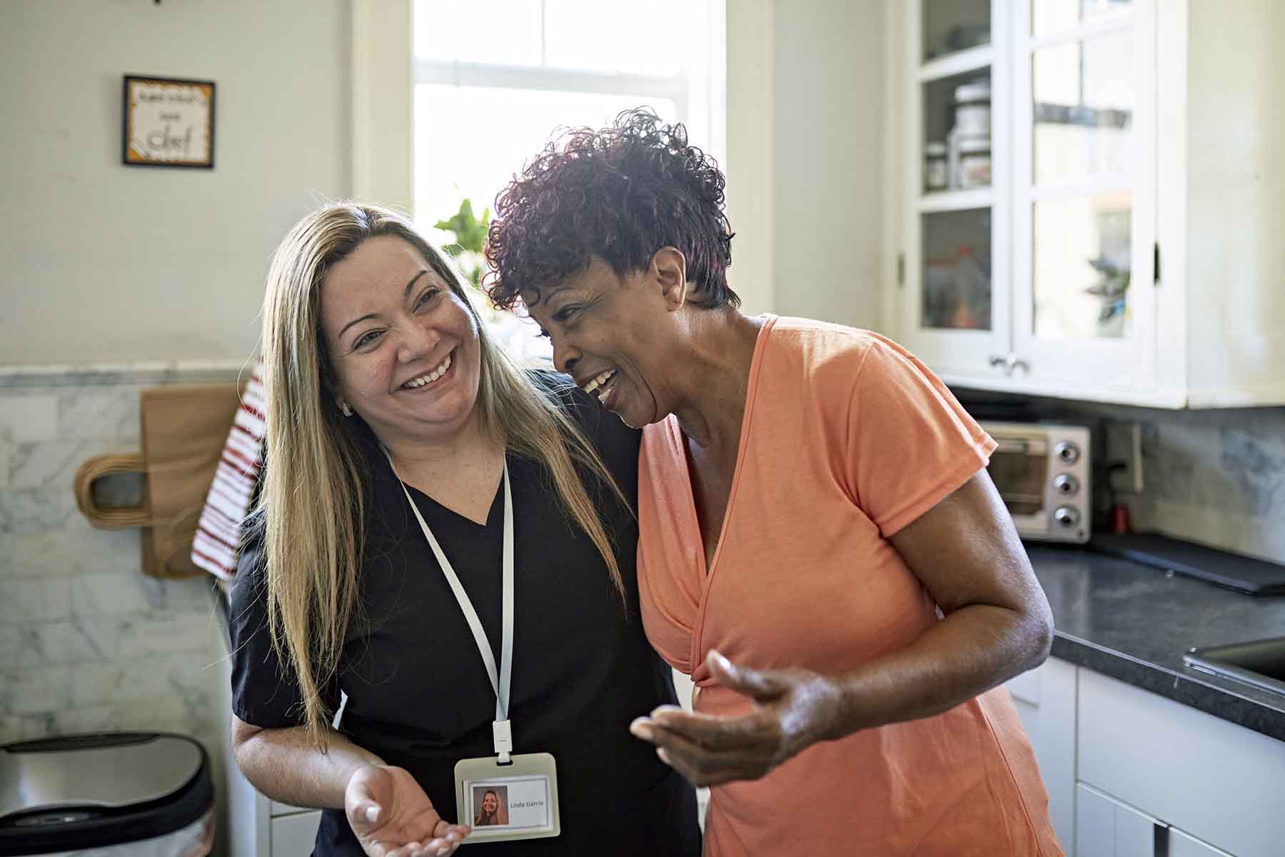 Senior woman and home caregiver together in kitchen