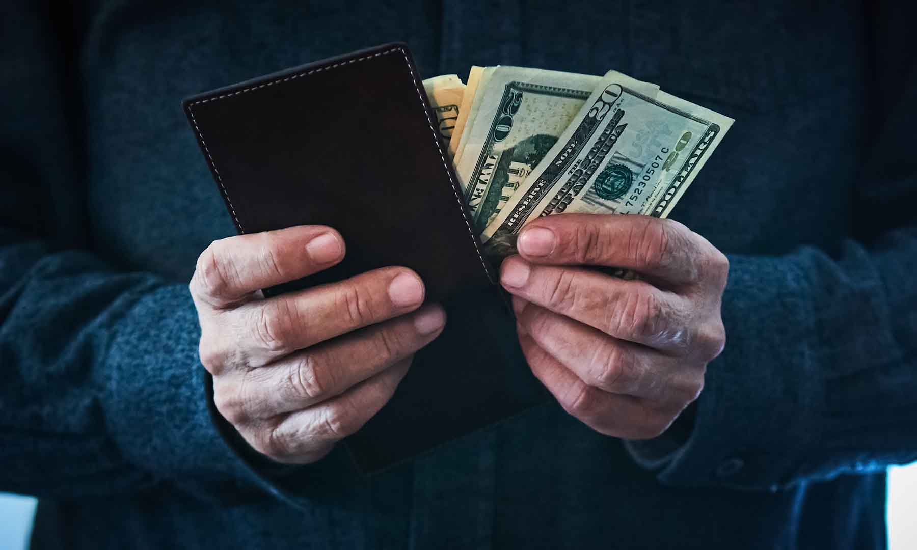 Closeup of a man's hands while he holds his open wallet