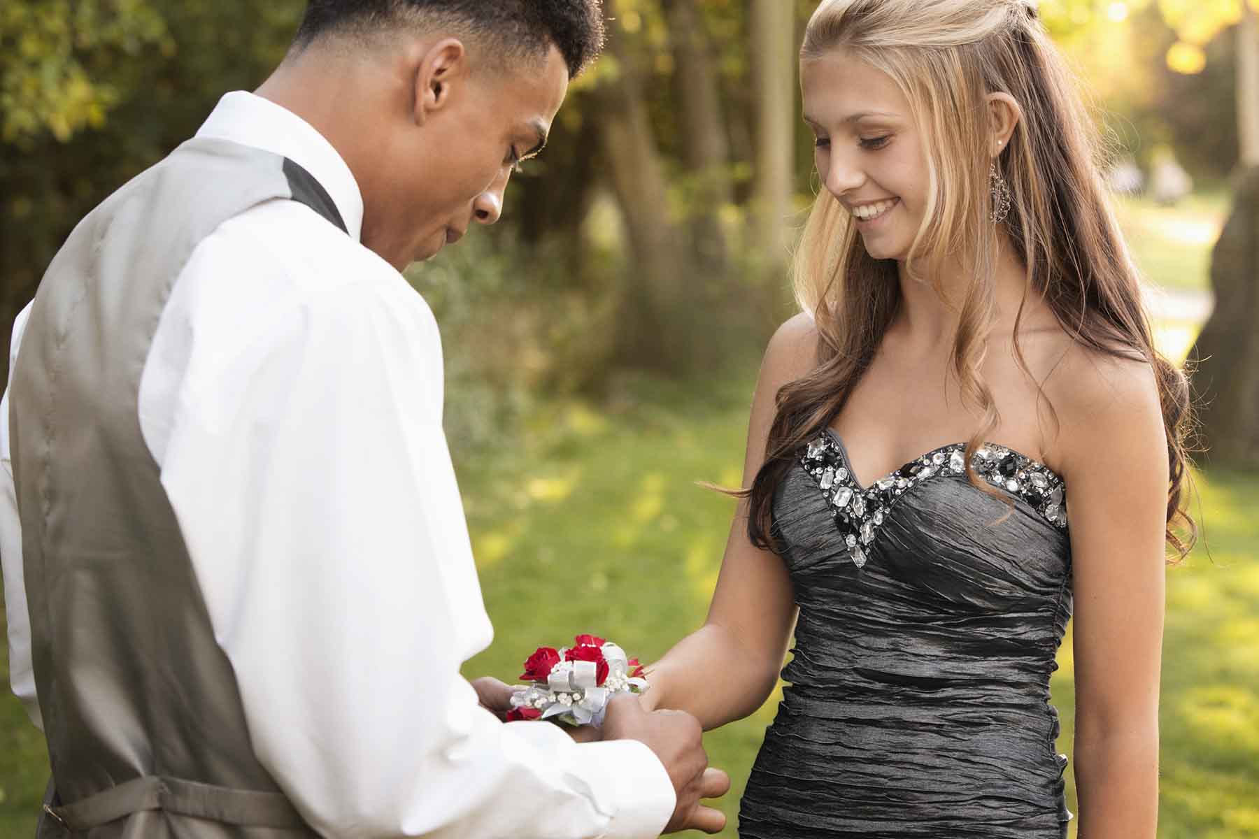 Teenage boy attaching a corsage to his prom date