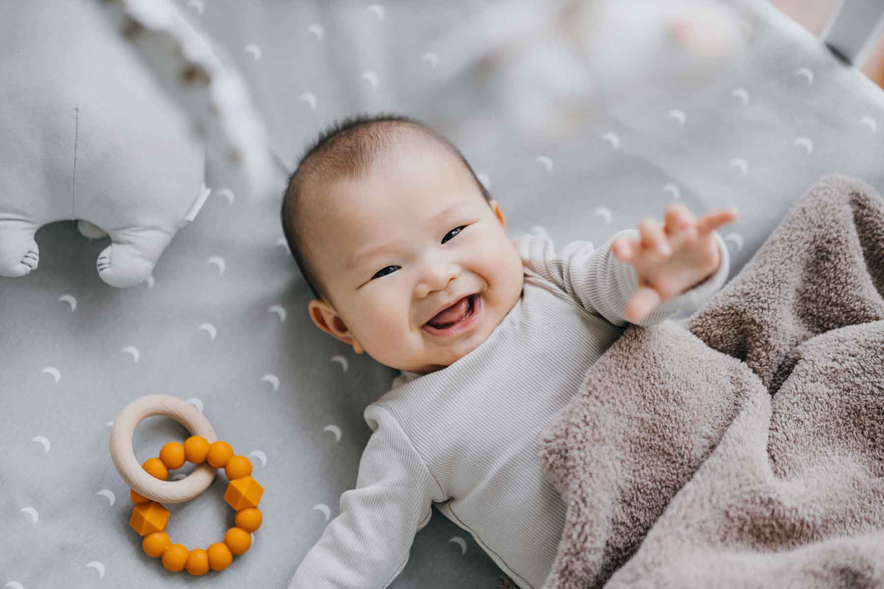 A smiling baby reaches toward the camera