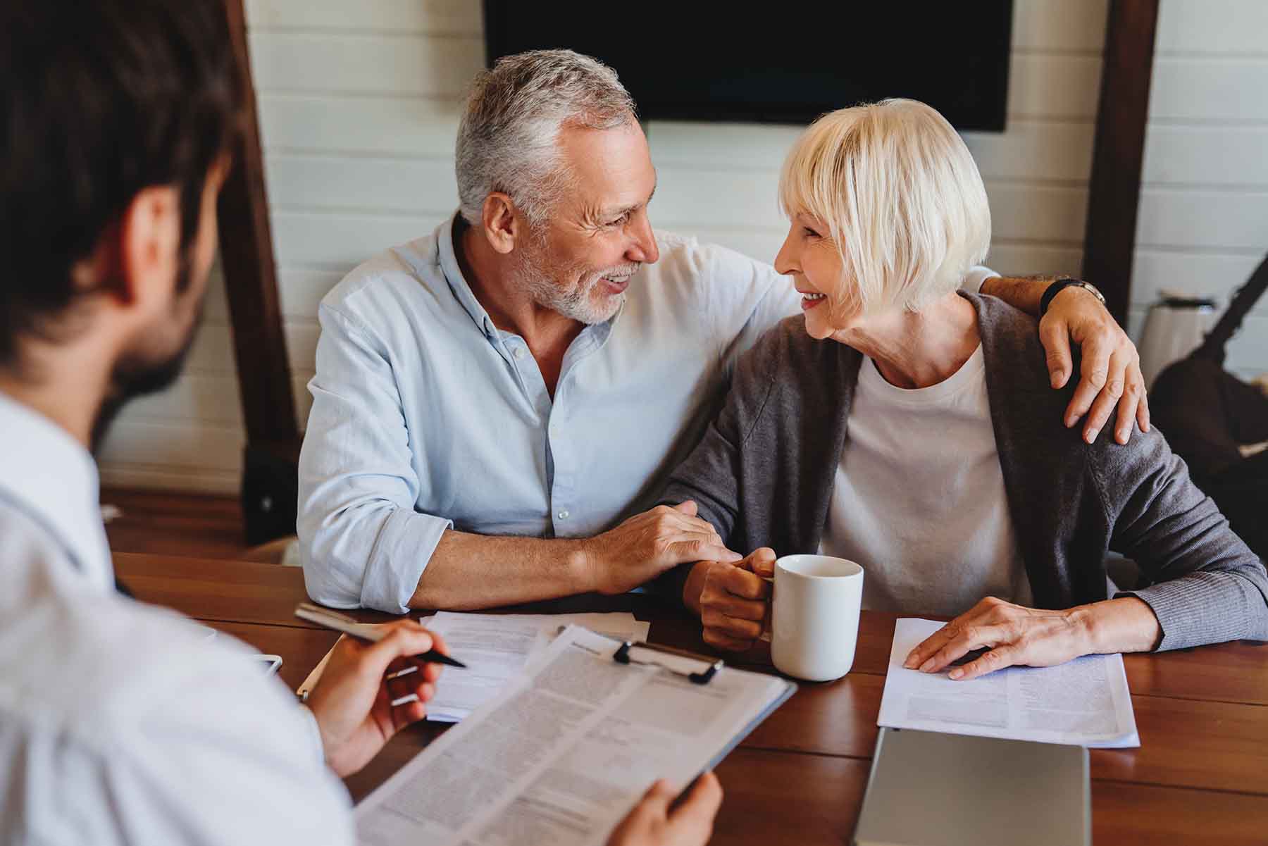 A mature couple smiles as they work with a financial advisor.