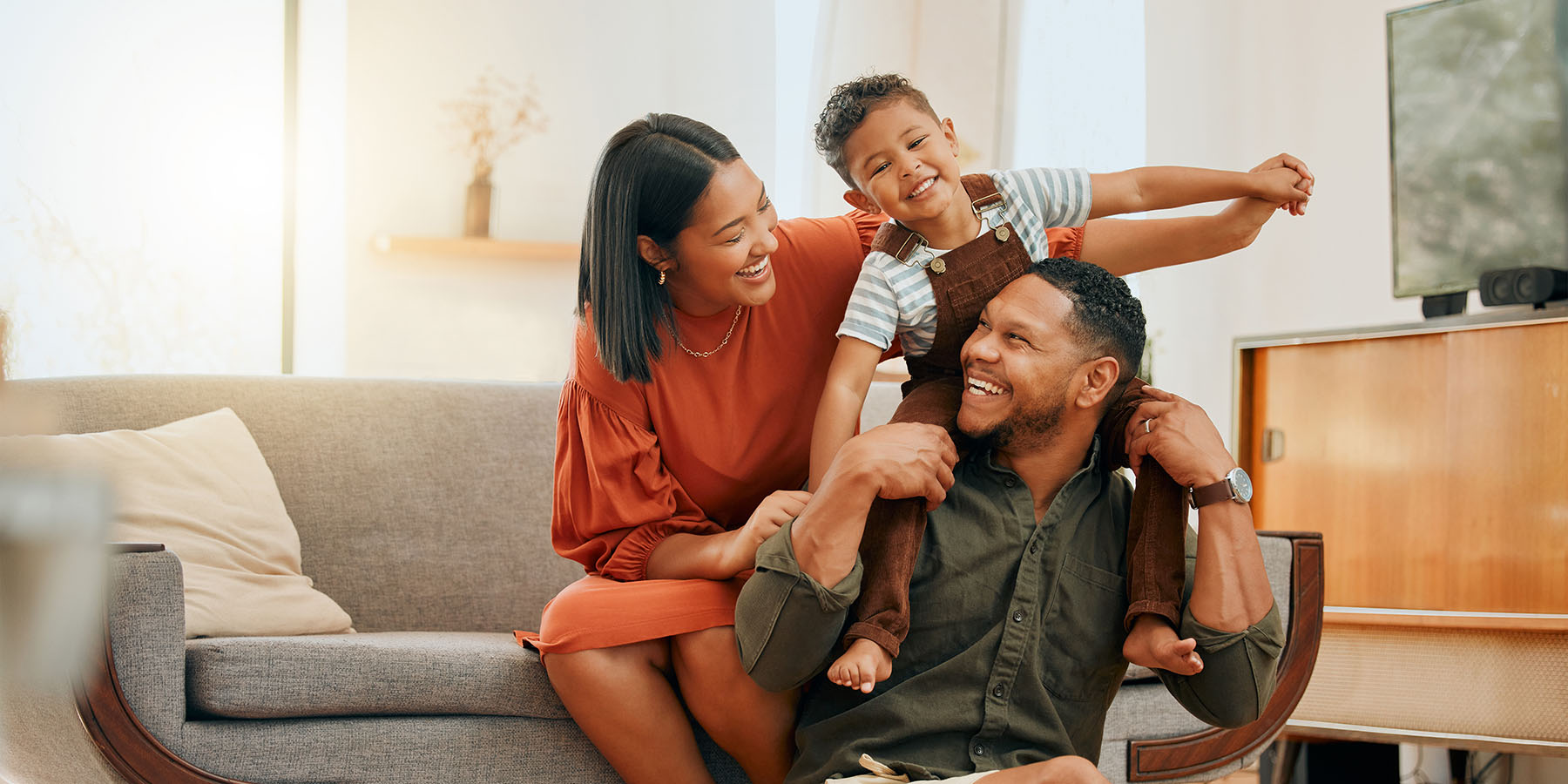 A young family smiling and sitting together in their living room