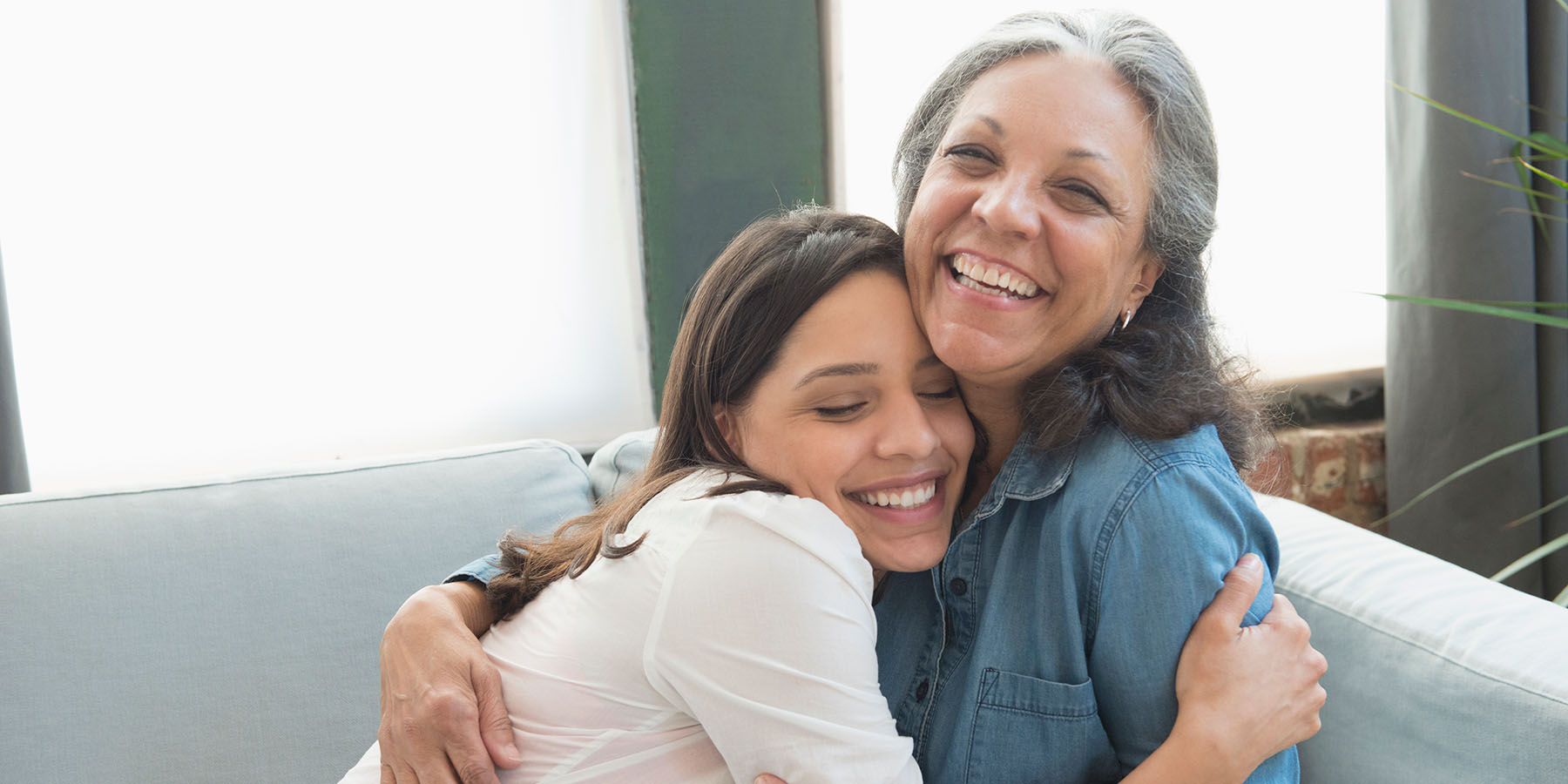 Adult child hugger her mother on the couch
