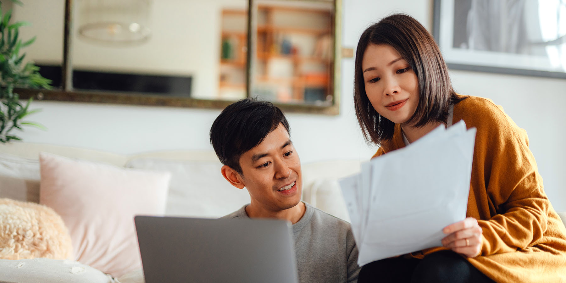 A couple sits in their living room reviewing their financial statements