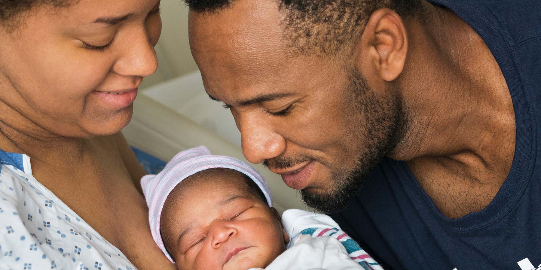 Parents looking admiringly at and holding their newborn baby in the hospital