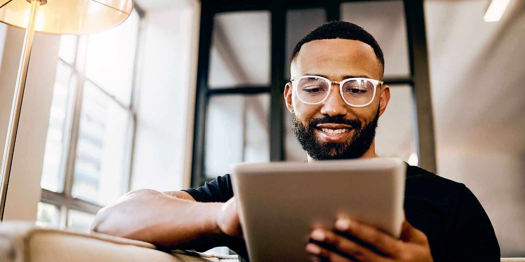 A young man sitting in his living room on a tablet