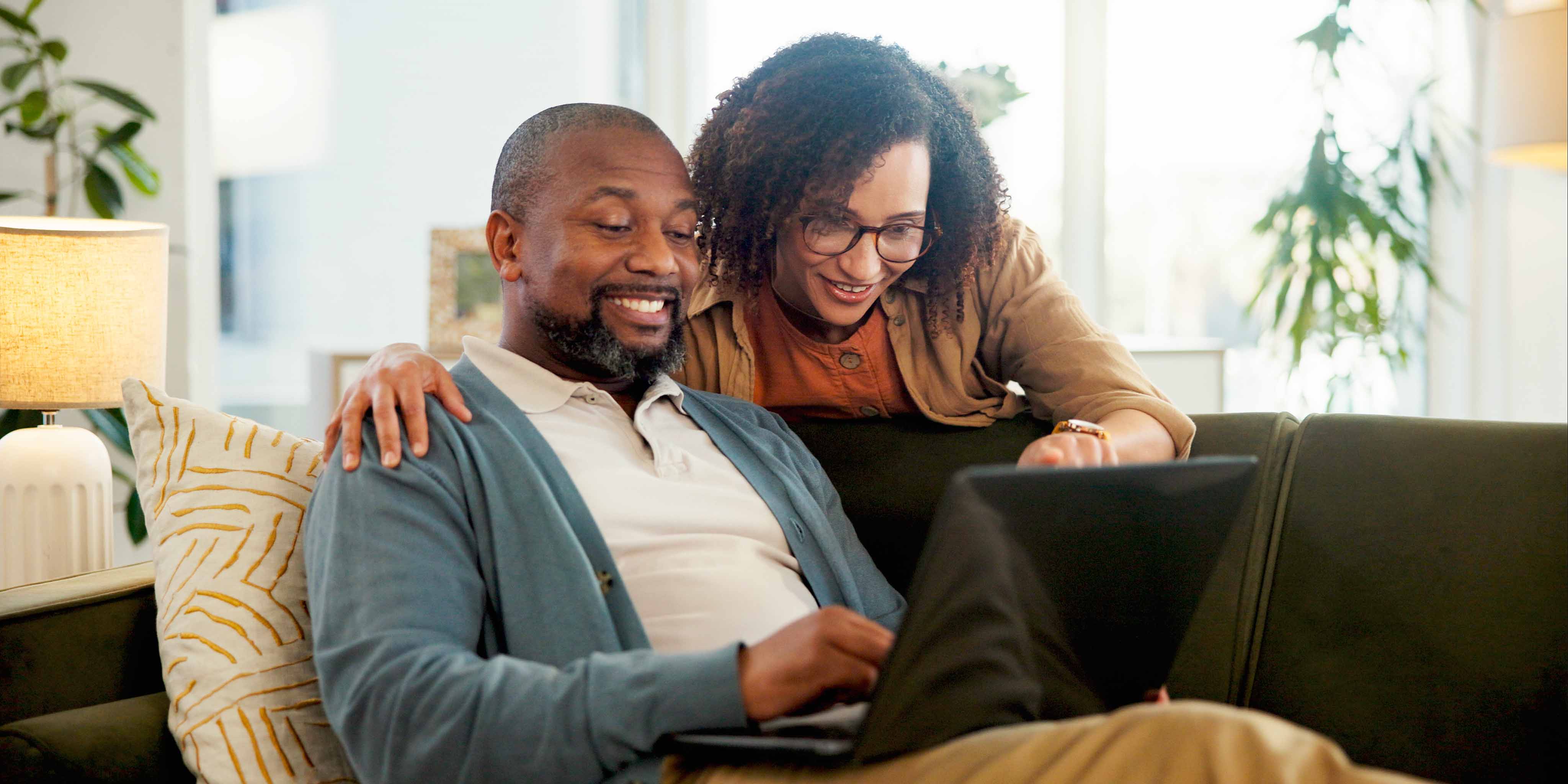 A woman pointing at something on a man's laptop