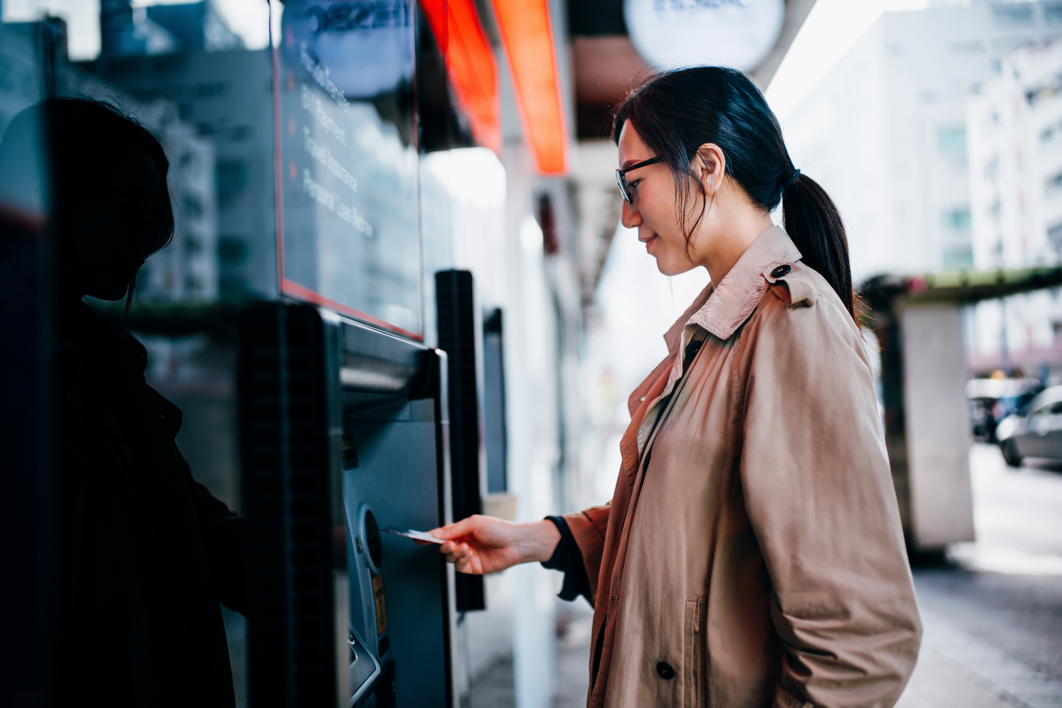 Women inserting debit card into ATM.