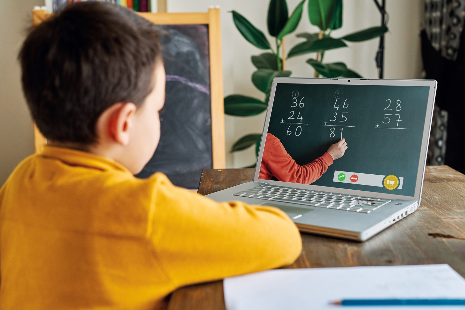 boy sitting at table looking at laptop for school