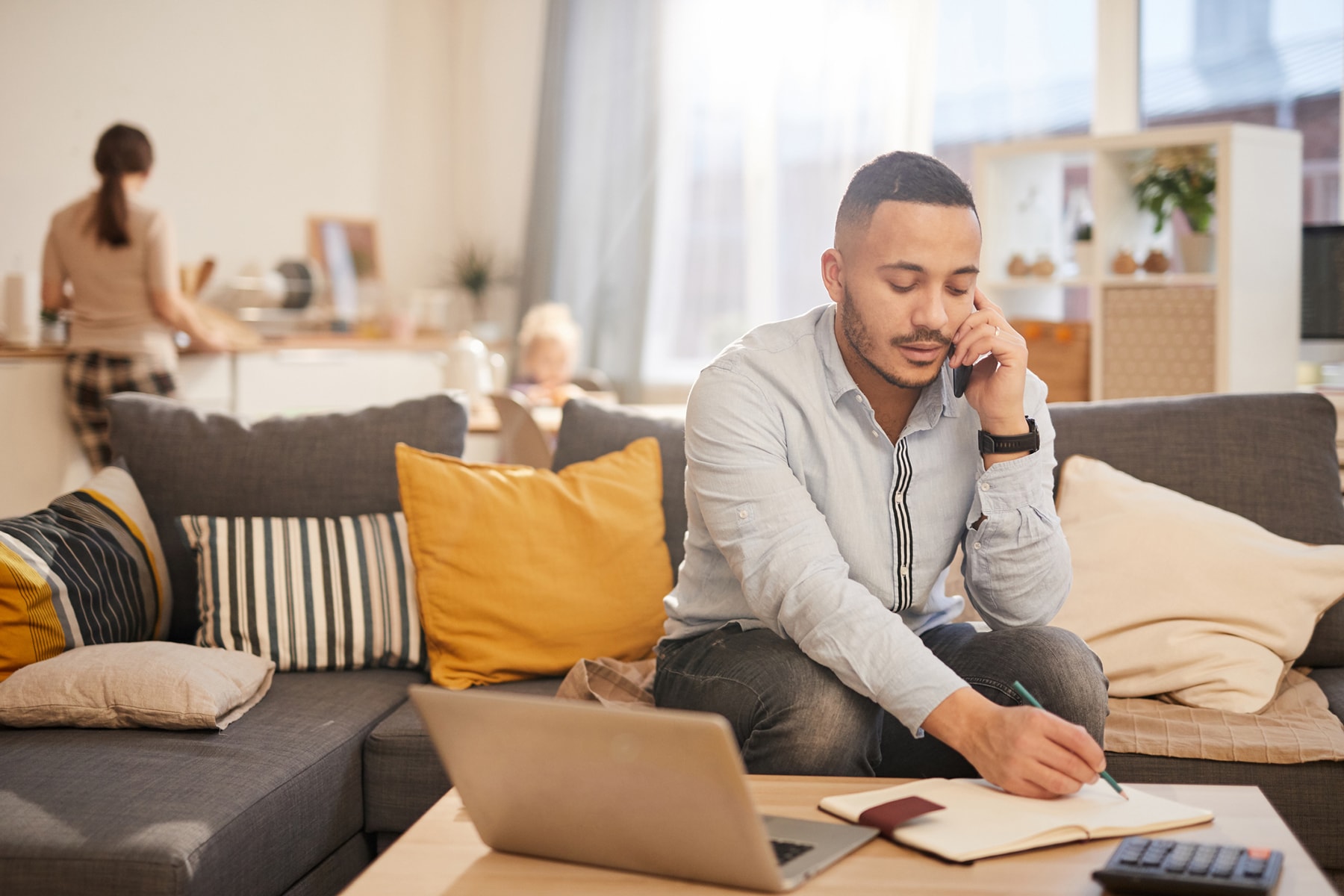 Man working on his cellphone and laptop in his living room