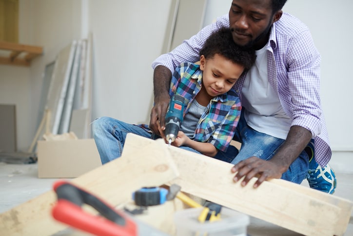 Dad and son drilling hole into piece of wood
