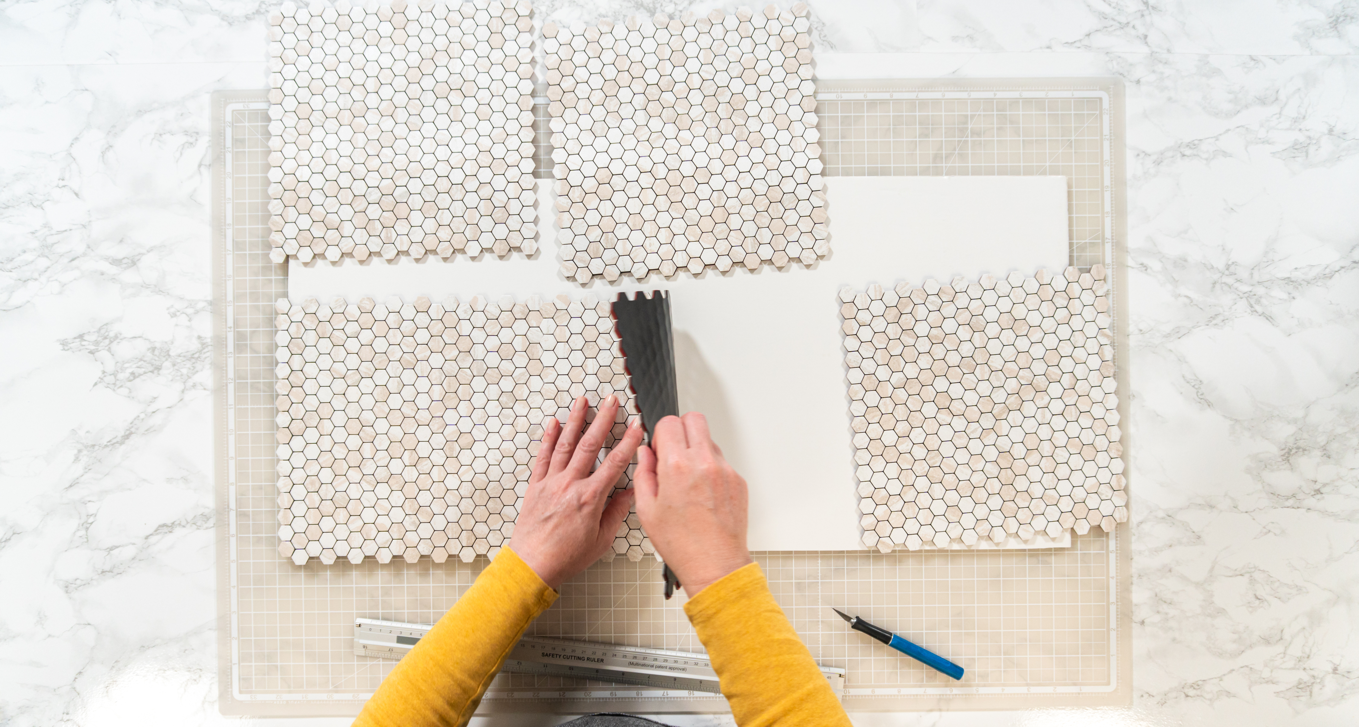 someone peeling the back off of backsplash to stick on