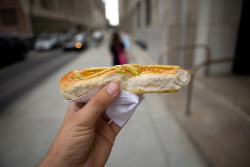 hand holding a pretzel bun with mustard on top