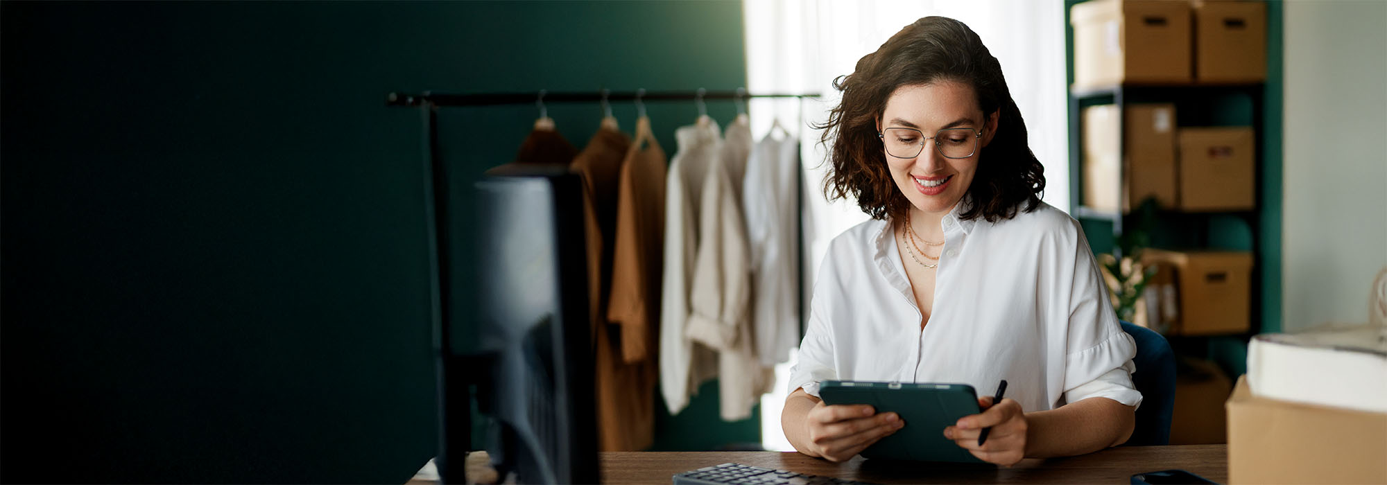 A woman on an iPad at a work desk