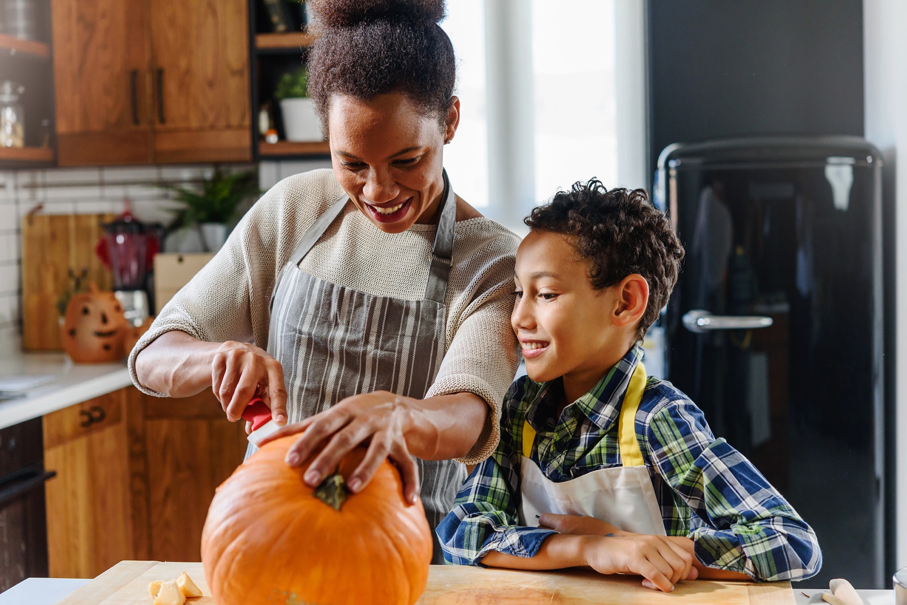 Mother and son carve a pumpkin in the kitchen