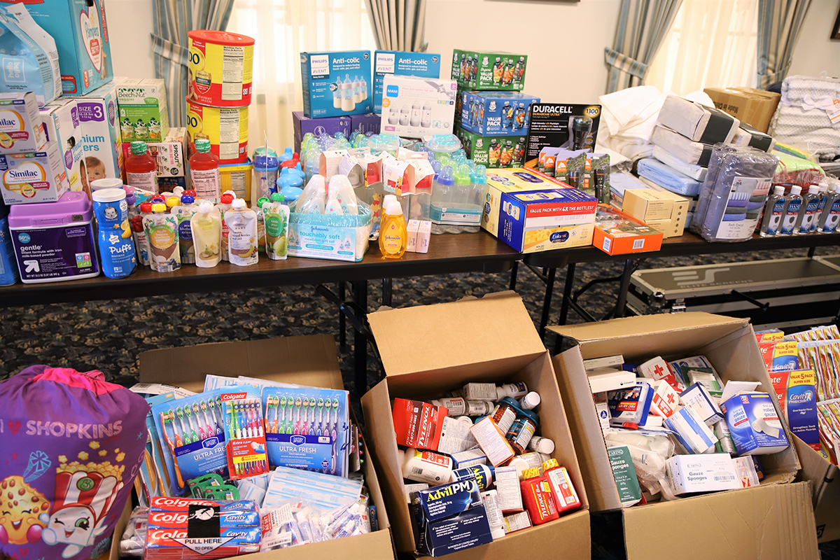 Donation items of baby formula, food, first aid essentials, toiletries and more fill table and boxes.
