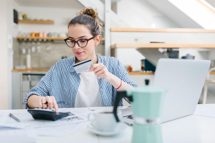 Woman planning out budget with card and computer