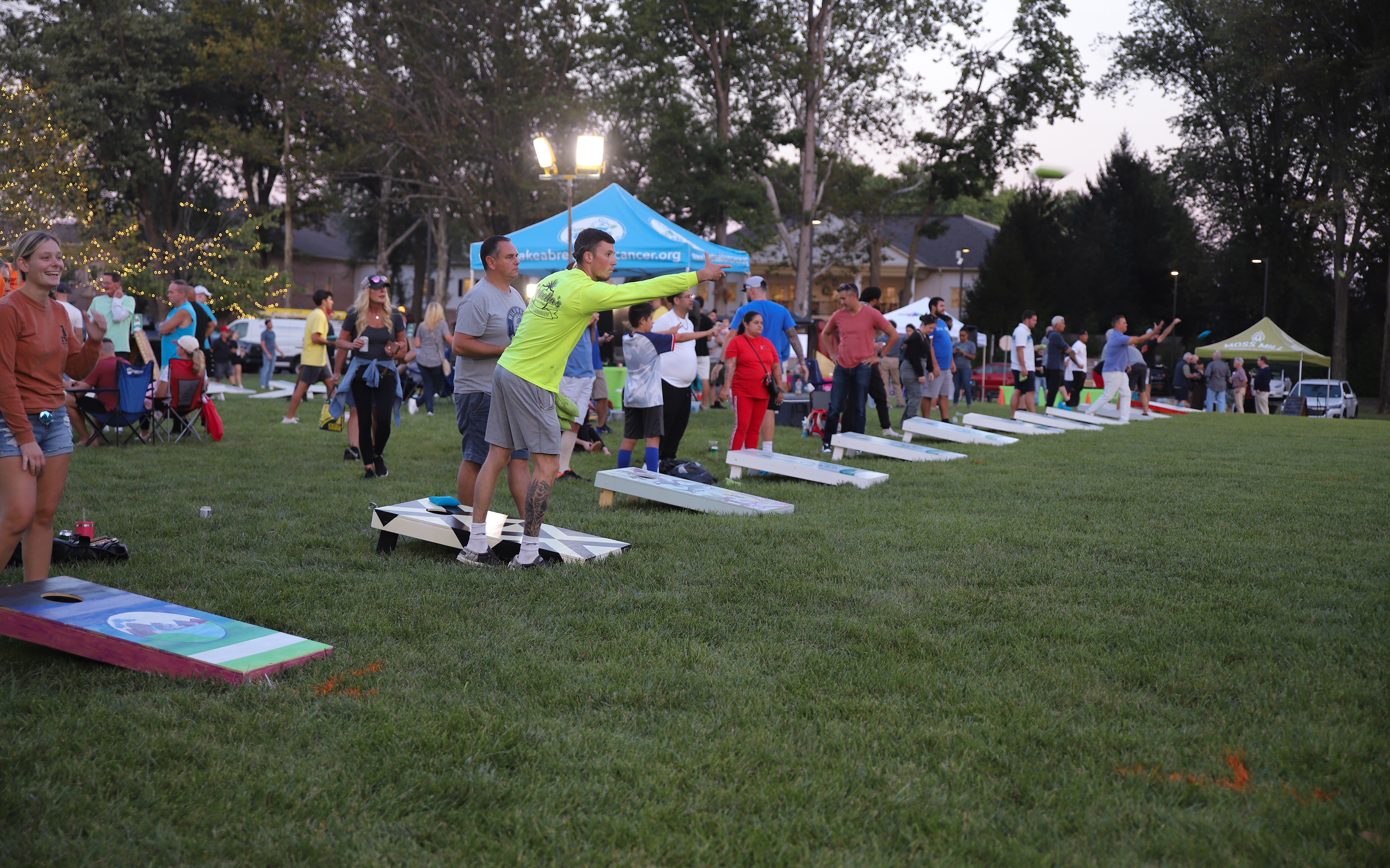 Cornhole players stand by line of cornhole boards to play in the second annual Kids-N-Hope Cornhole Tournament.