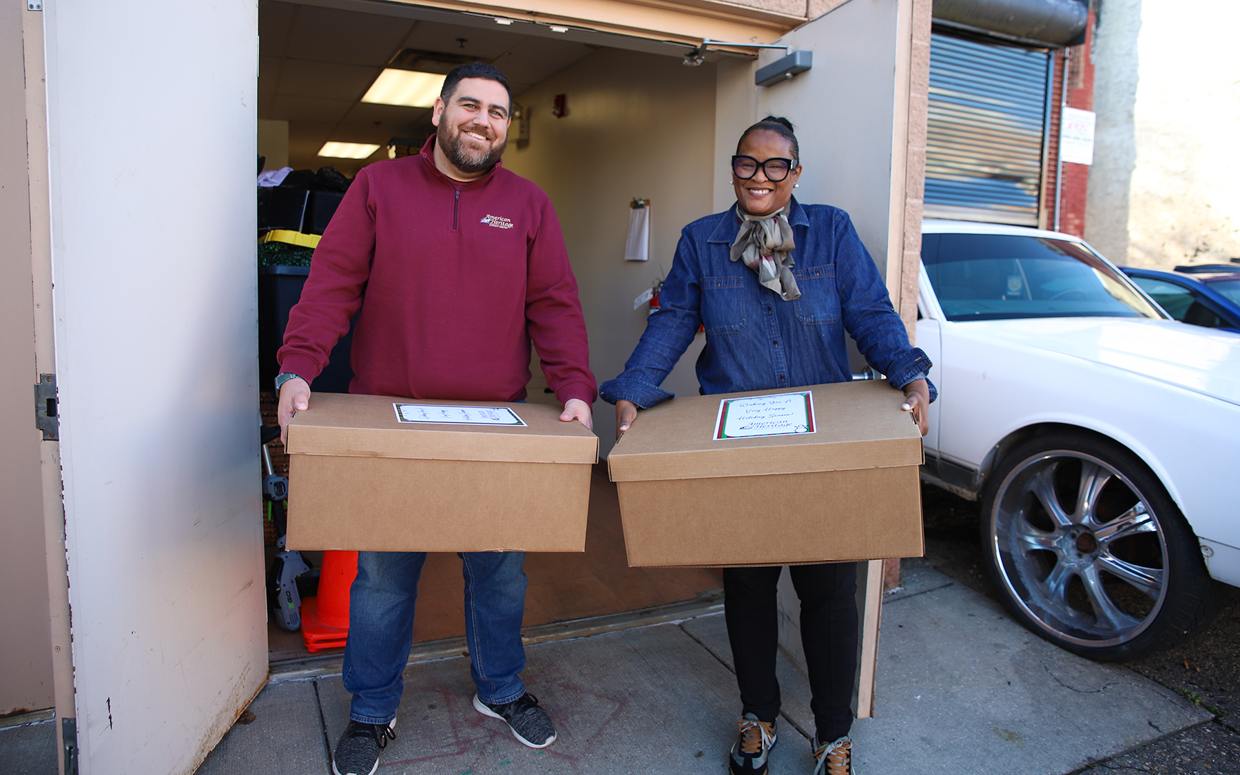 To individuals hold meal boxes which were donated by American Heritage Credit Union.